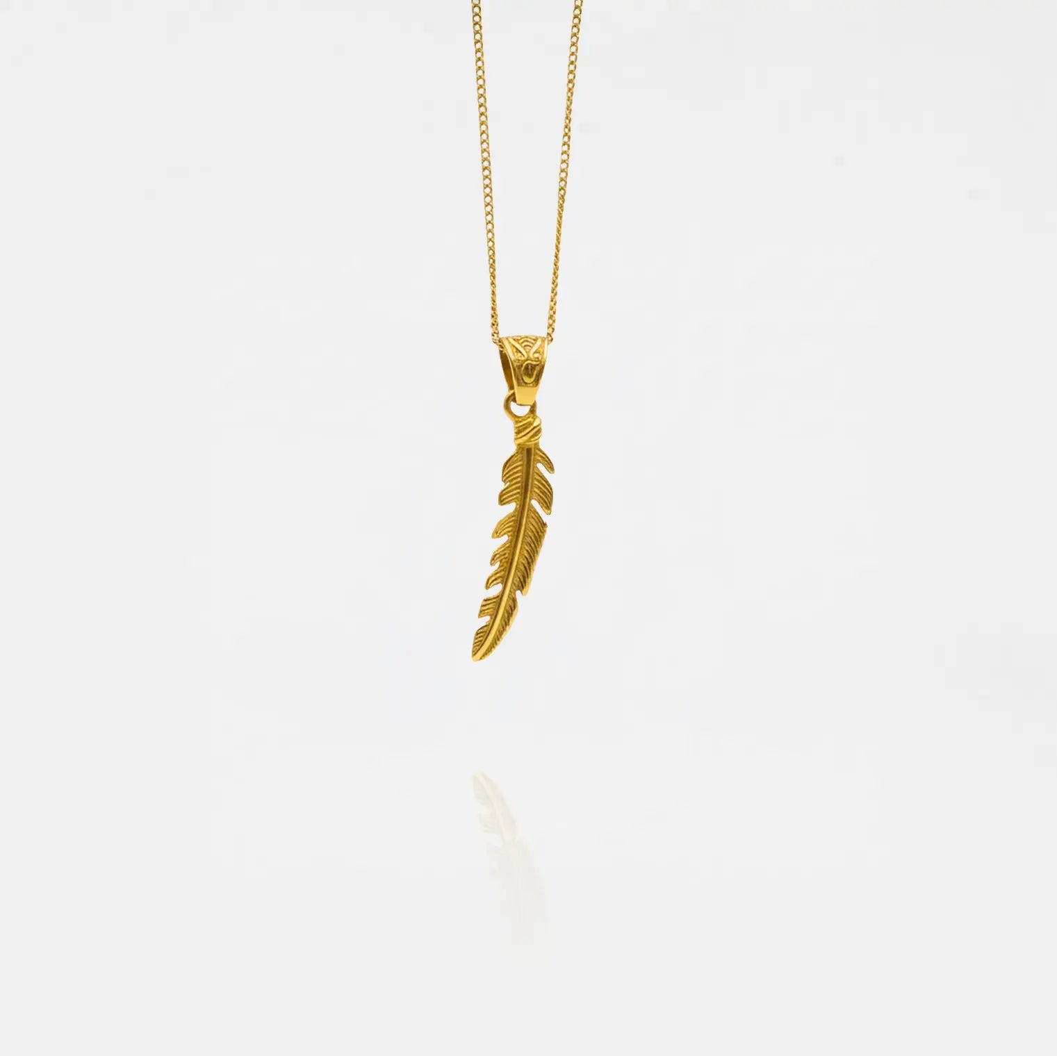 Gold feather pendant necklace on a white background