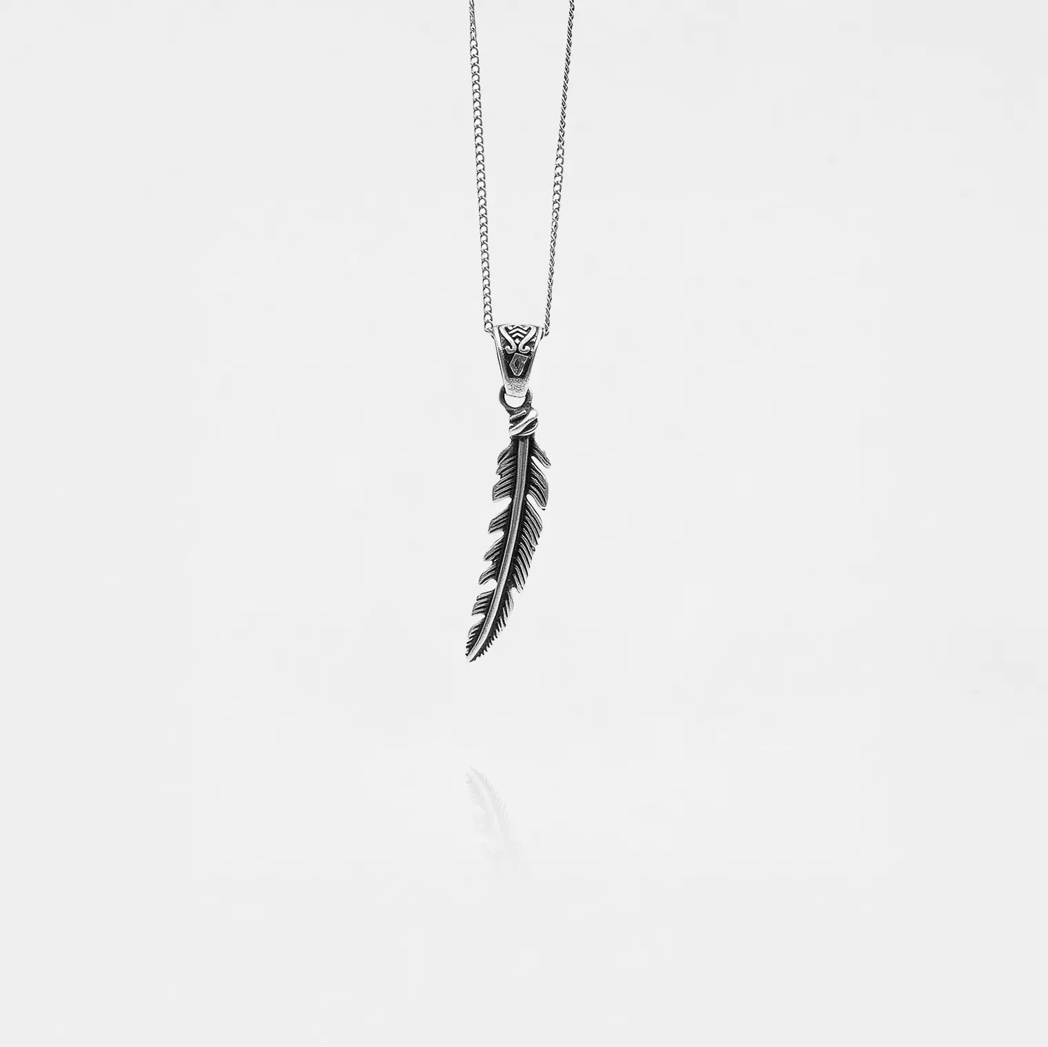 Silver feather pendant necklace on a white background