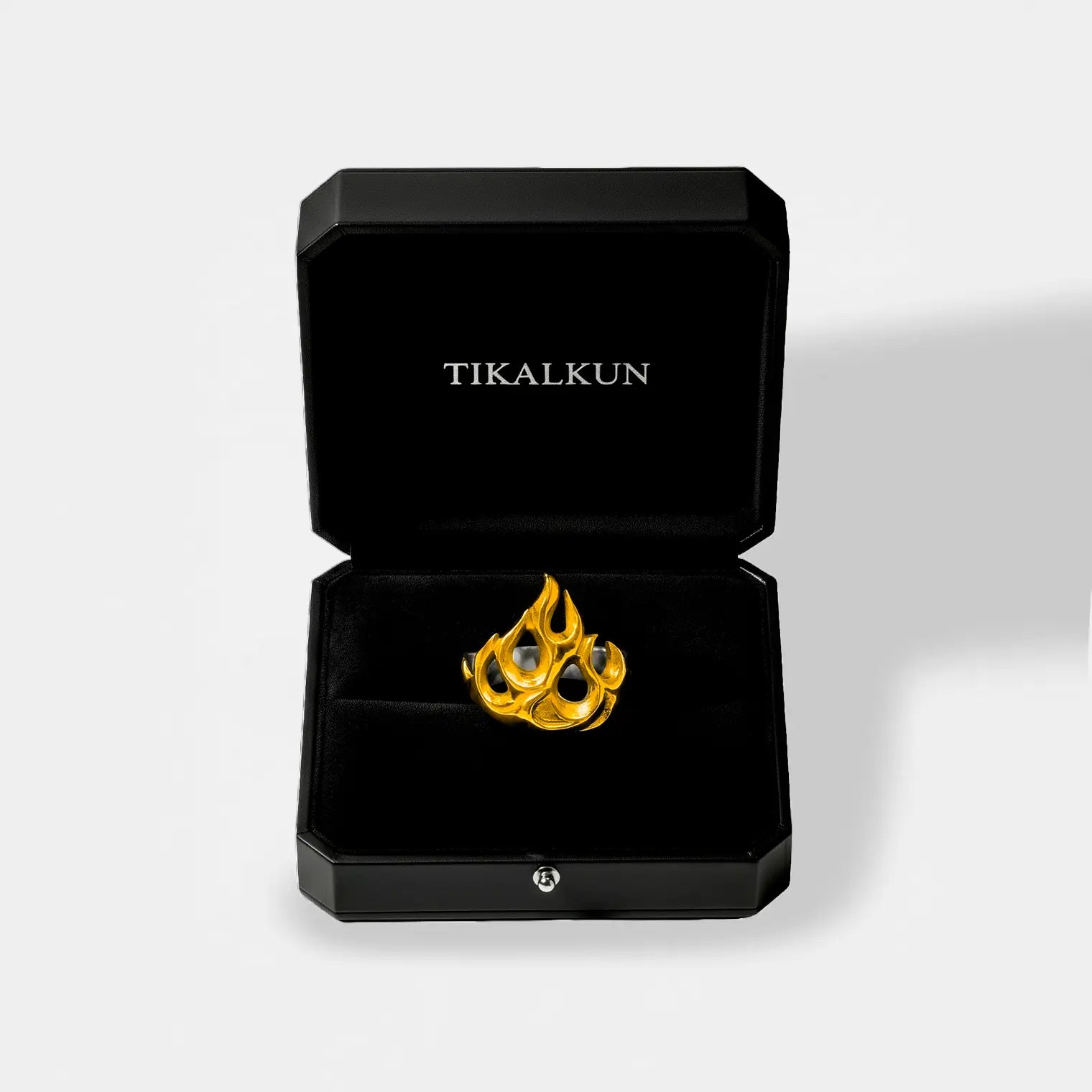 Gold ring with a fire-flame design in a black Tikalkun box on a light gray background
