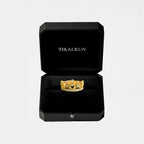 Gold ring with a crown design in a black Tikalkun box on a light gray background