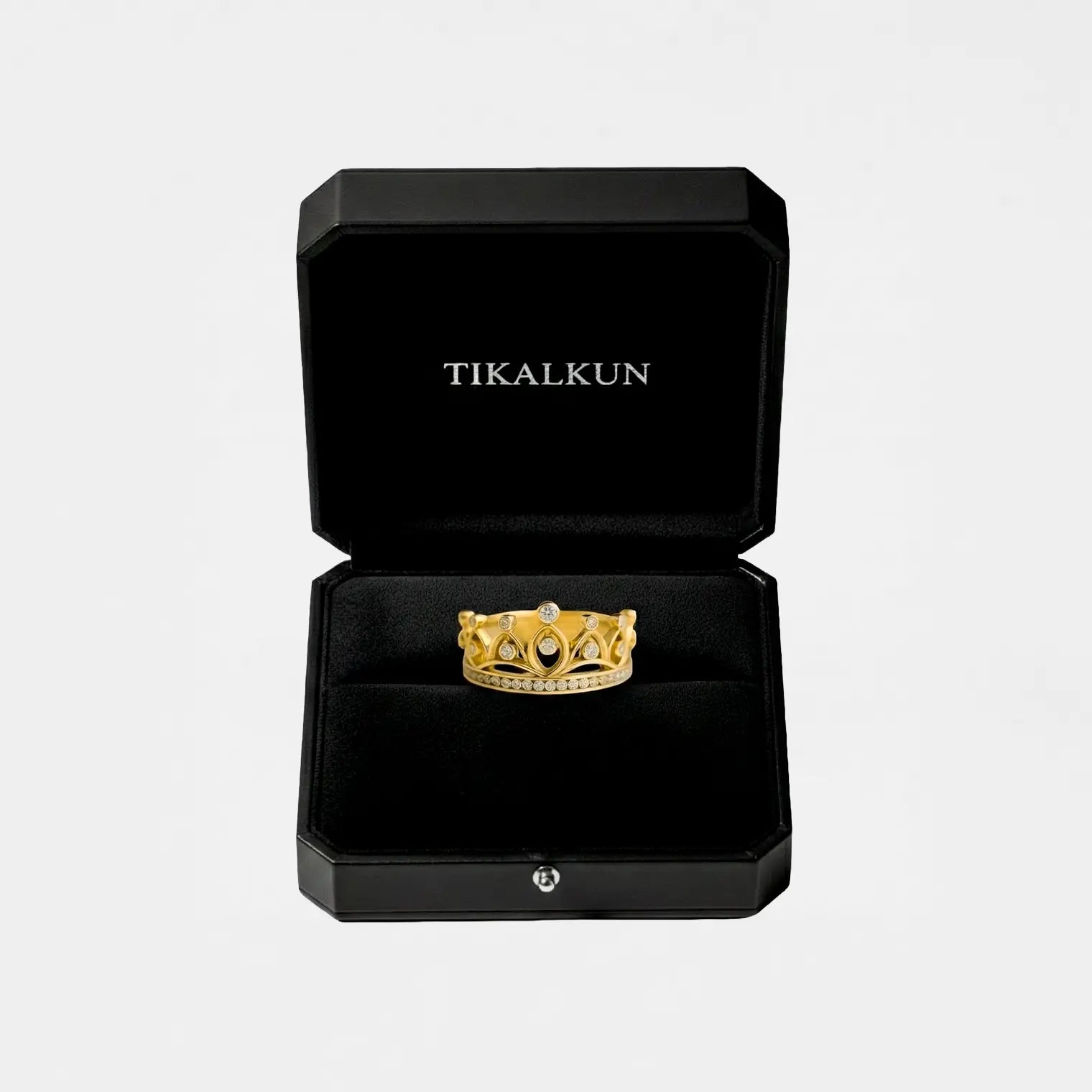 Gold ring with a crown design in a black Tikalkun box on a light gray background