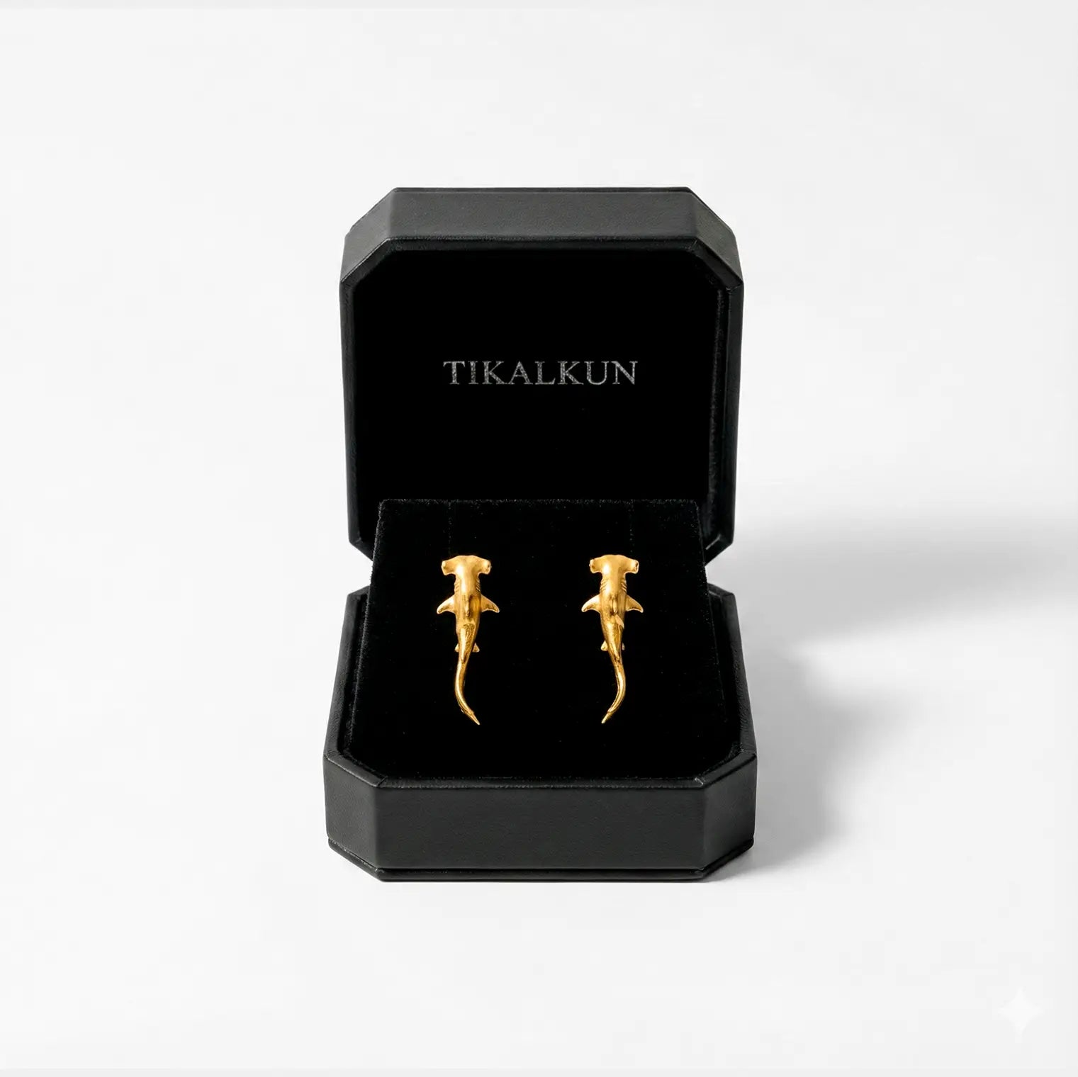 Gold  hammerhead-shark earrings in a black Tikalkun box on a white background