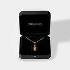 Gold hammerhead-shark necklace in a black Tikalkun jewelry box on a light gray background