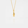 Gold necklace with a small hammerhead-shark pendant on a light gray background