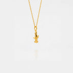 Gold necklace with a small hammerhead-shark pendant on a light gray background