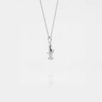Silver necklace with a small hammerhead-shark pendant on a light gray background