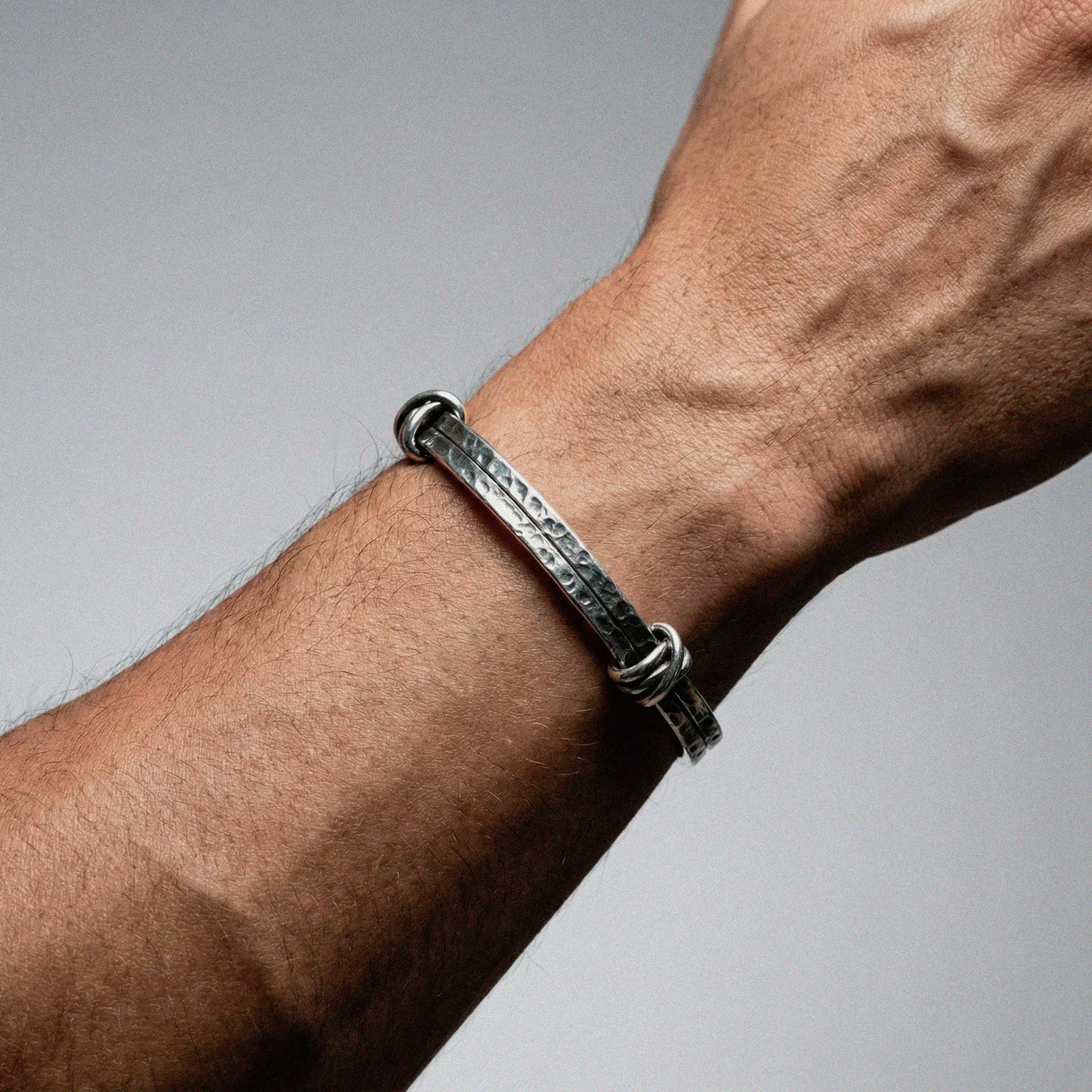 Silver bracelet on a wrist with a gray background