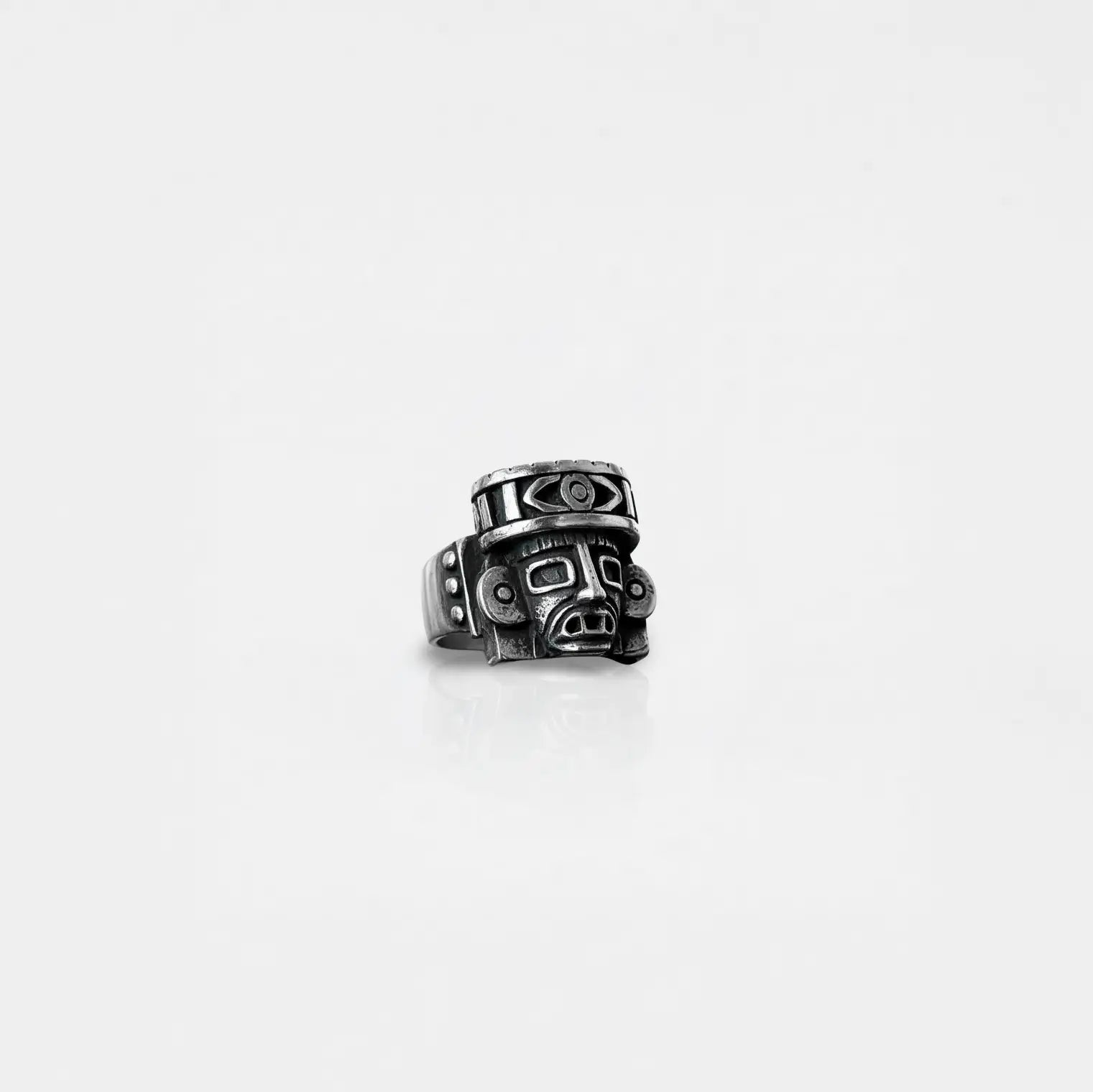 Silver ring with aztec god design on a white background
