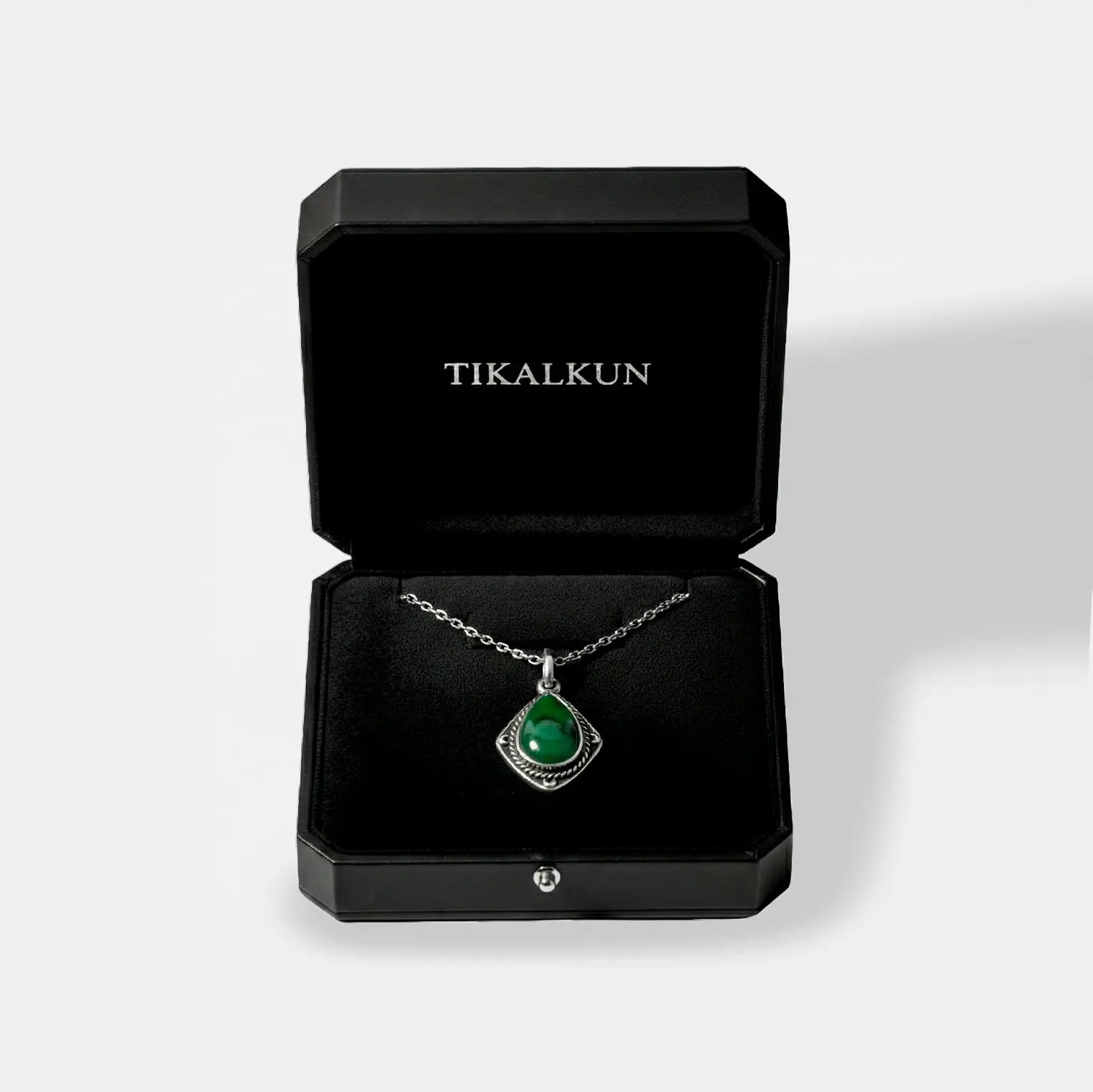 Jewelry box with an jade necklace and 'TIKALKUN' branding on a light gray background