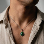 Necklace with a green jade stone pendant worn by a person wearing a beige shirt.