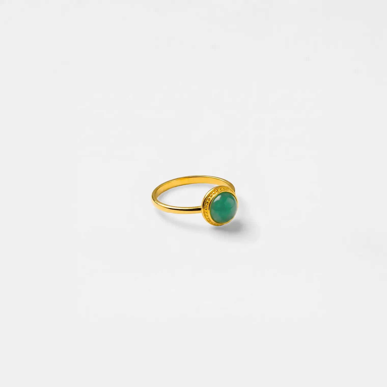 Gold ring with a green gemstone on a white background
