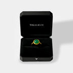 Gold ring with a jade gemstone in a black Tikalkun jewelry box on a light gray background