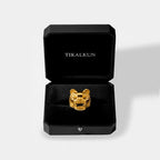 Gold jaguar head pendant in a black Tikalkun jewelry box on a light gray background