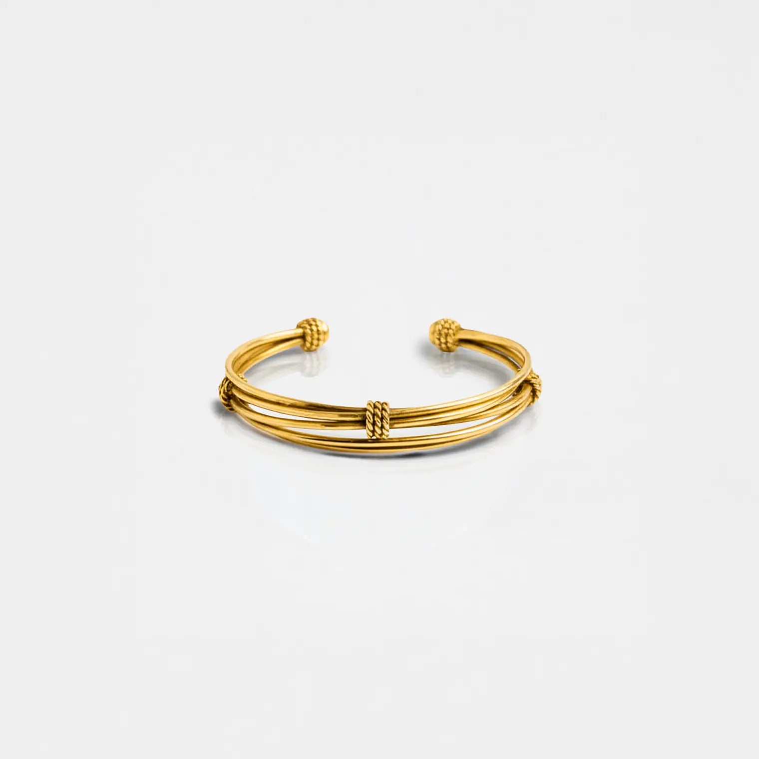 Gold bracelet on a light gray background