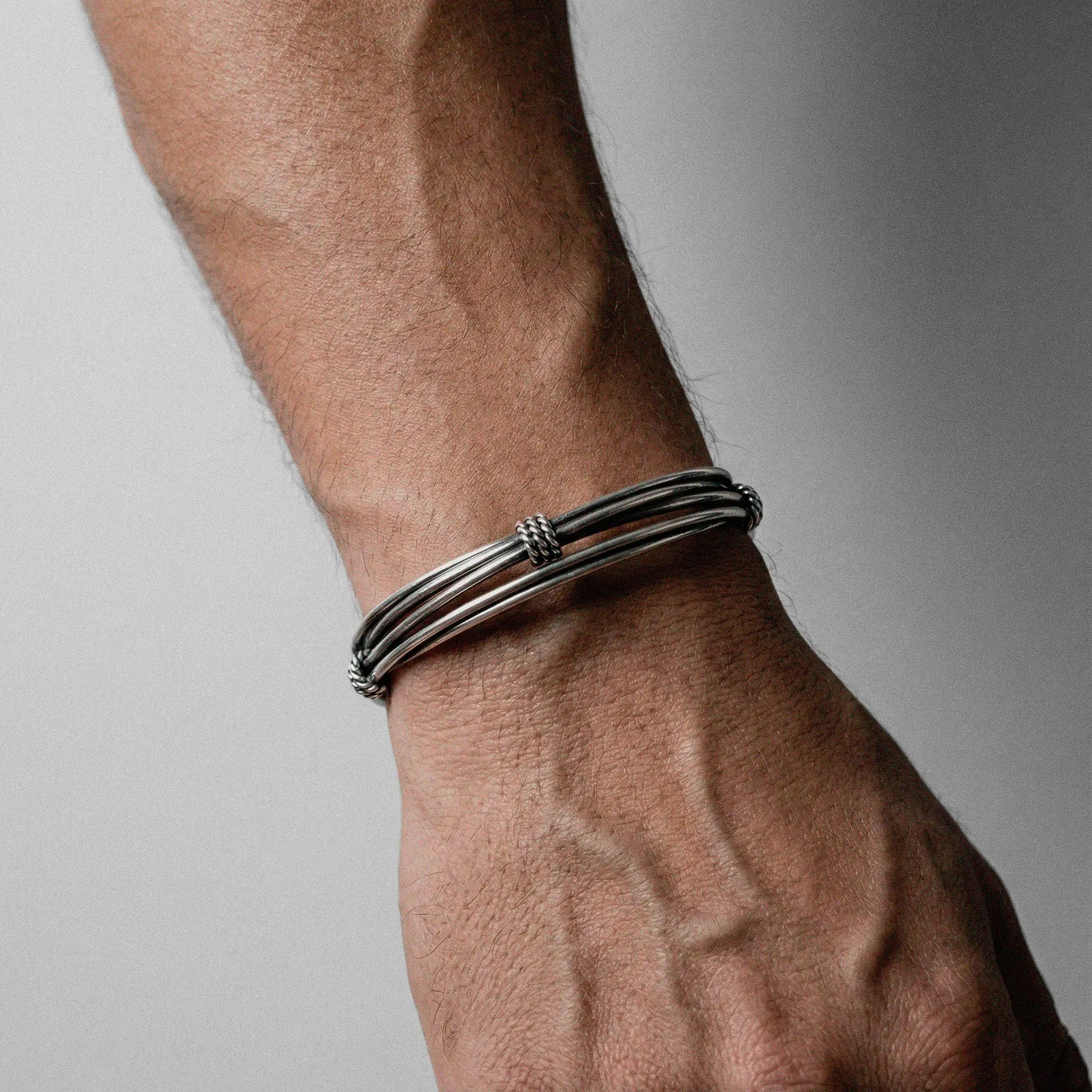 Close-up of a wrist wearing silver bracelet on a neutral background