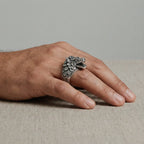 Hand wearing a kukulkan silver ring on a neutral background