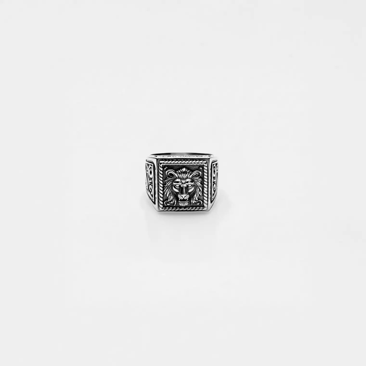 Silver ring with lion head design on a light gray background