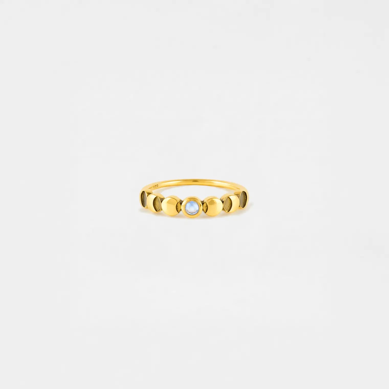 lunar cycle Gold ring with a central gemstone on a light gray background