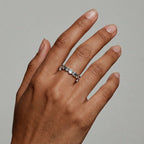 Hand wearing a silver lunar-phase ring with small stones on a neutral background