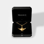 Gold manta ray necklace in a black Tikalkun jewelry box on a light gray background