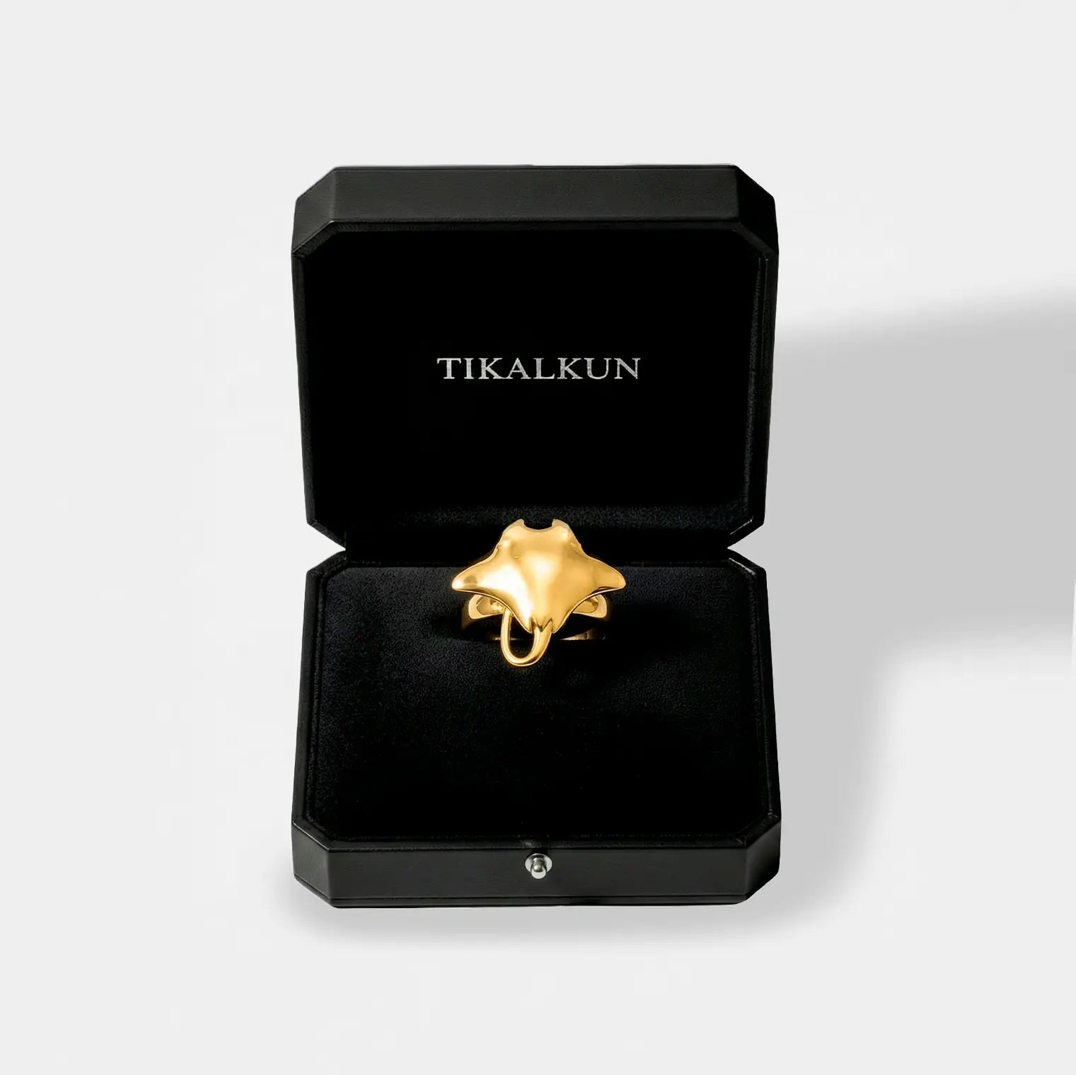Gold manta ray ring in a black Tikalkun jewelry box on a light gray background