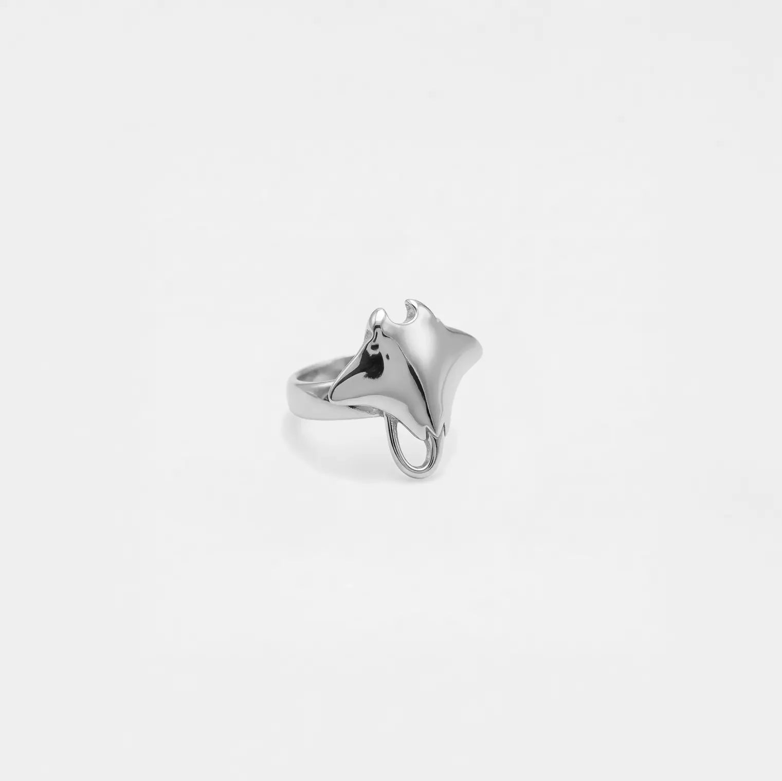 Silver ring with a manta ray design on a light gray background