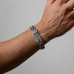 Silver mayan calendar bracelet on a wrist against a gray background