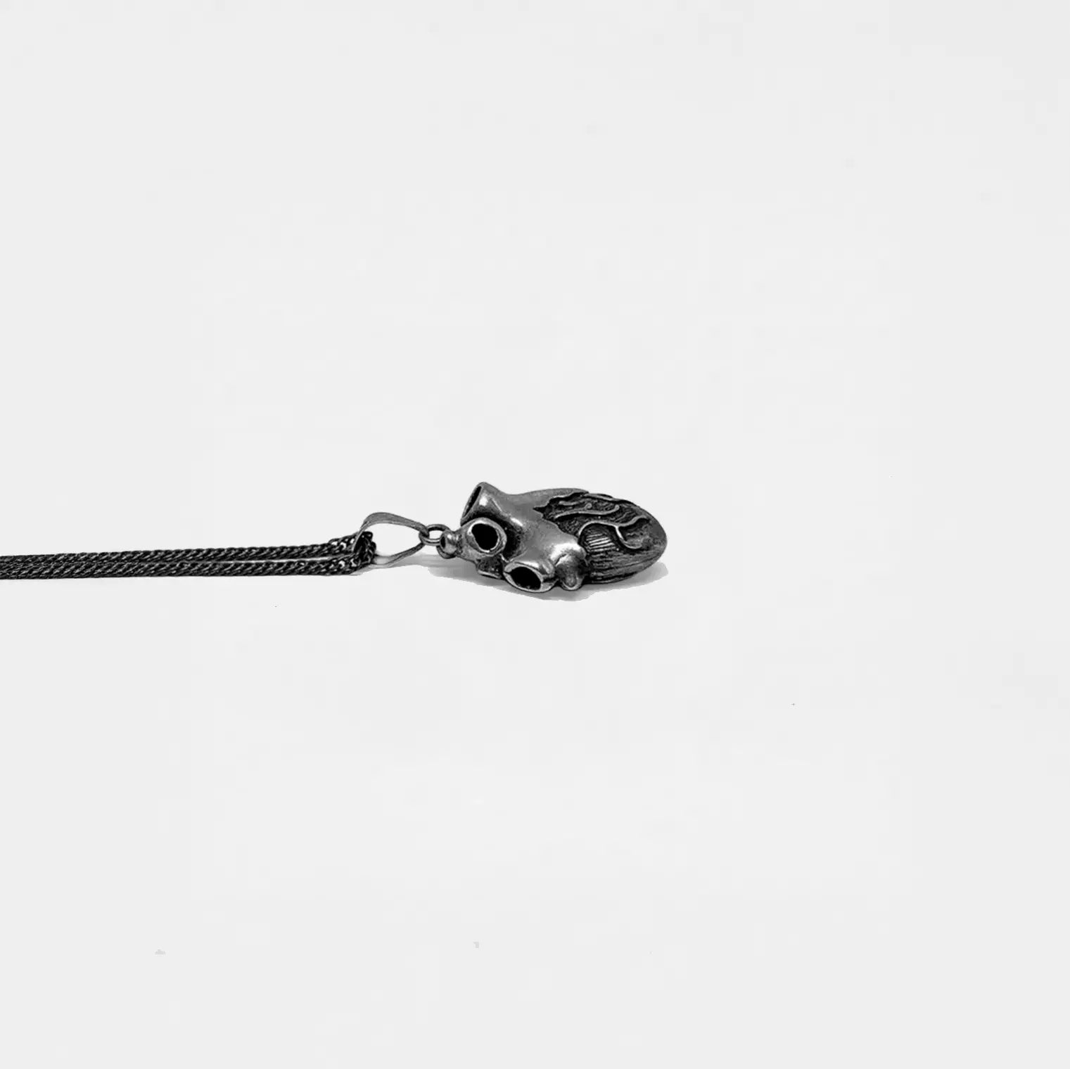 Silver heart pendant on a thin chain against a light gray background