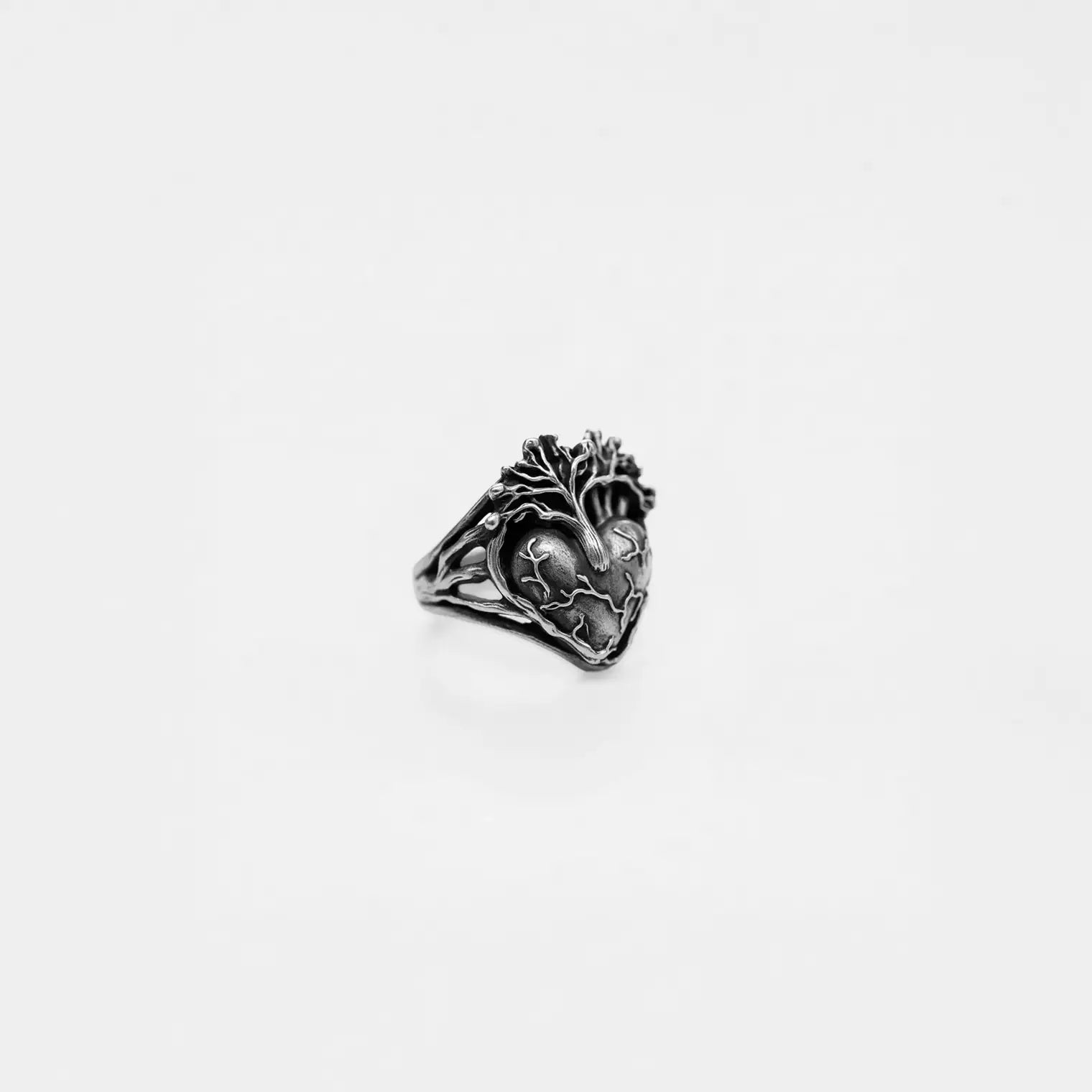 Silver ring with anatomical heart design on a light gray background