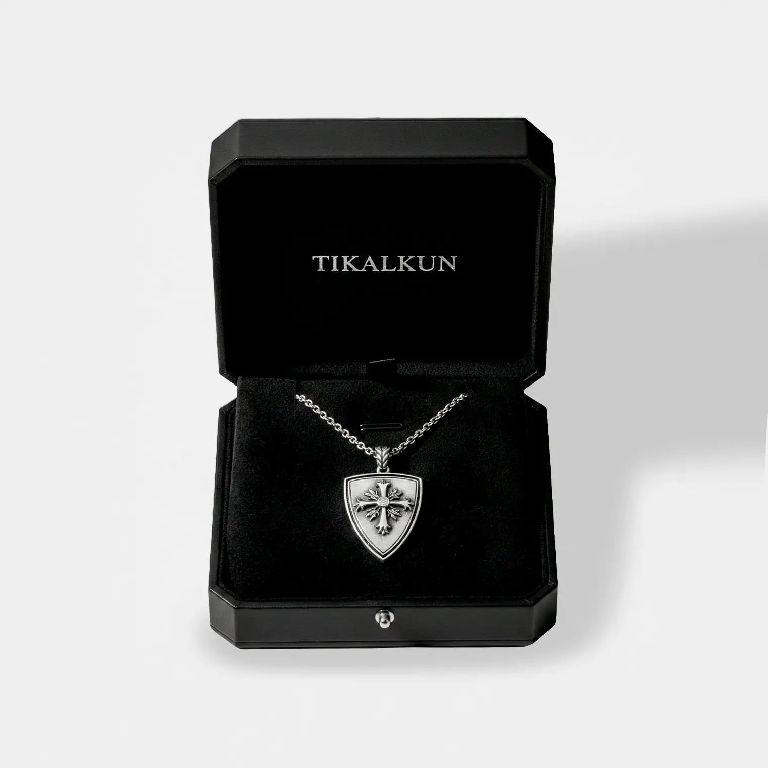 Silver necklace with a shield pendant in a black Tikalkun jewelry box on a light gray background