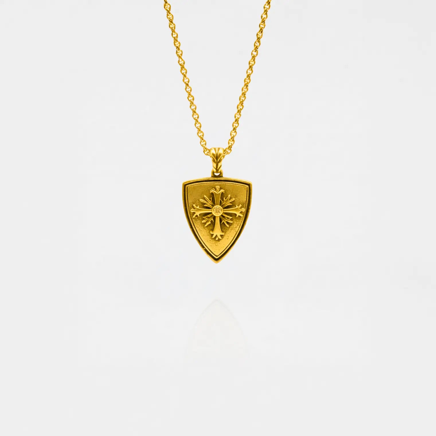 Gold necklace with a shield-shaped pendant on a white background