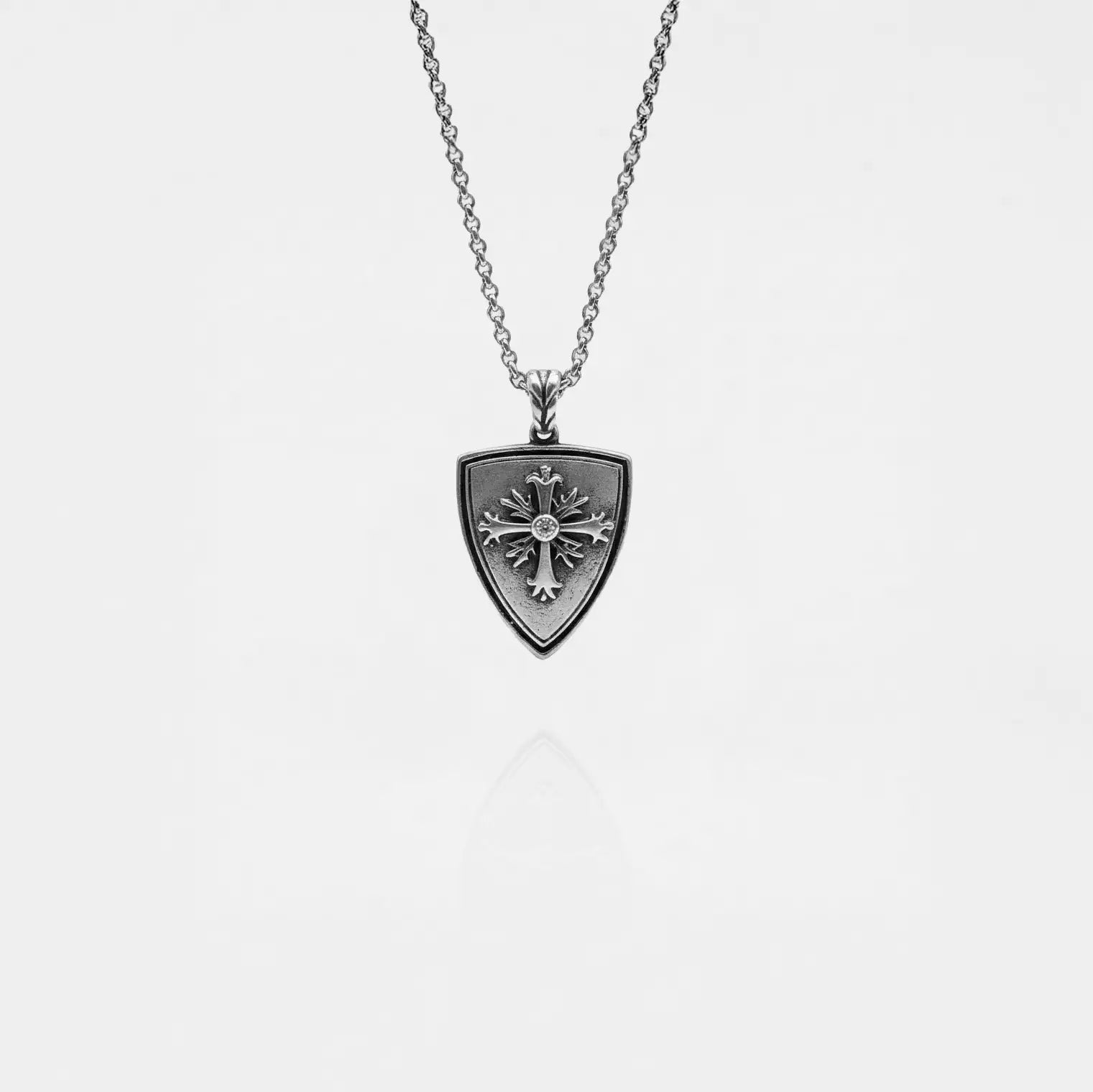 Silver necklace with a shield-shaped pendant on a light gray background