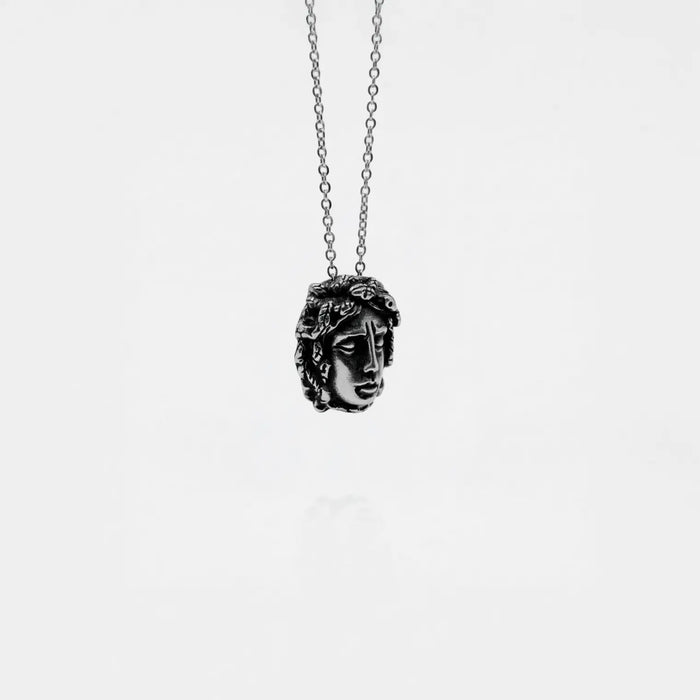 Necklace with a pendant shaped like a medusa head on a white background