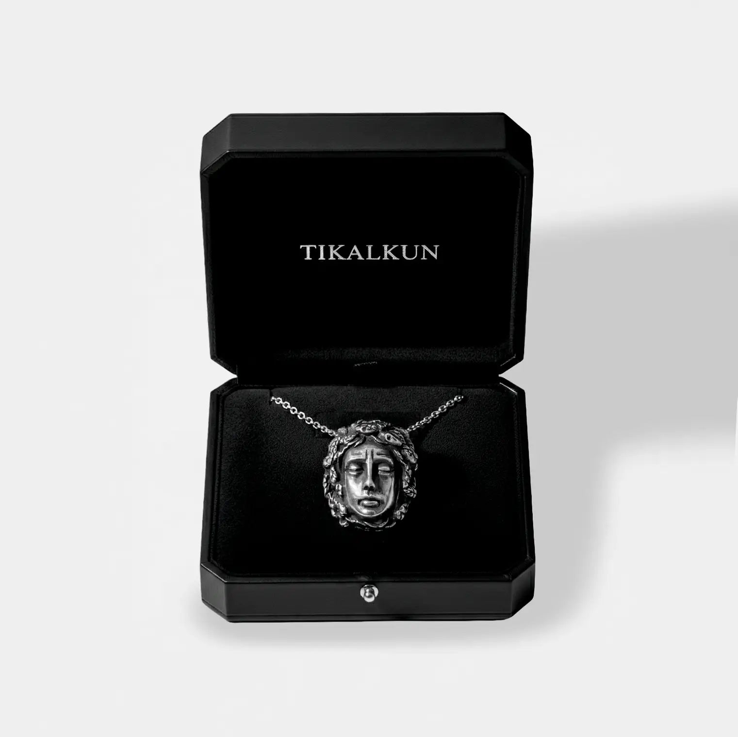Jewelry box with a necklace featuring a medusa head pendant, branded 'TIKALKUN'.