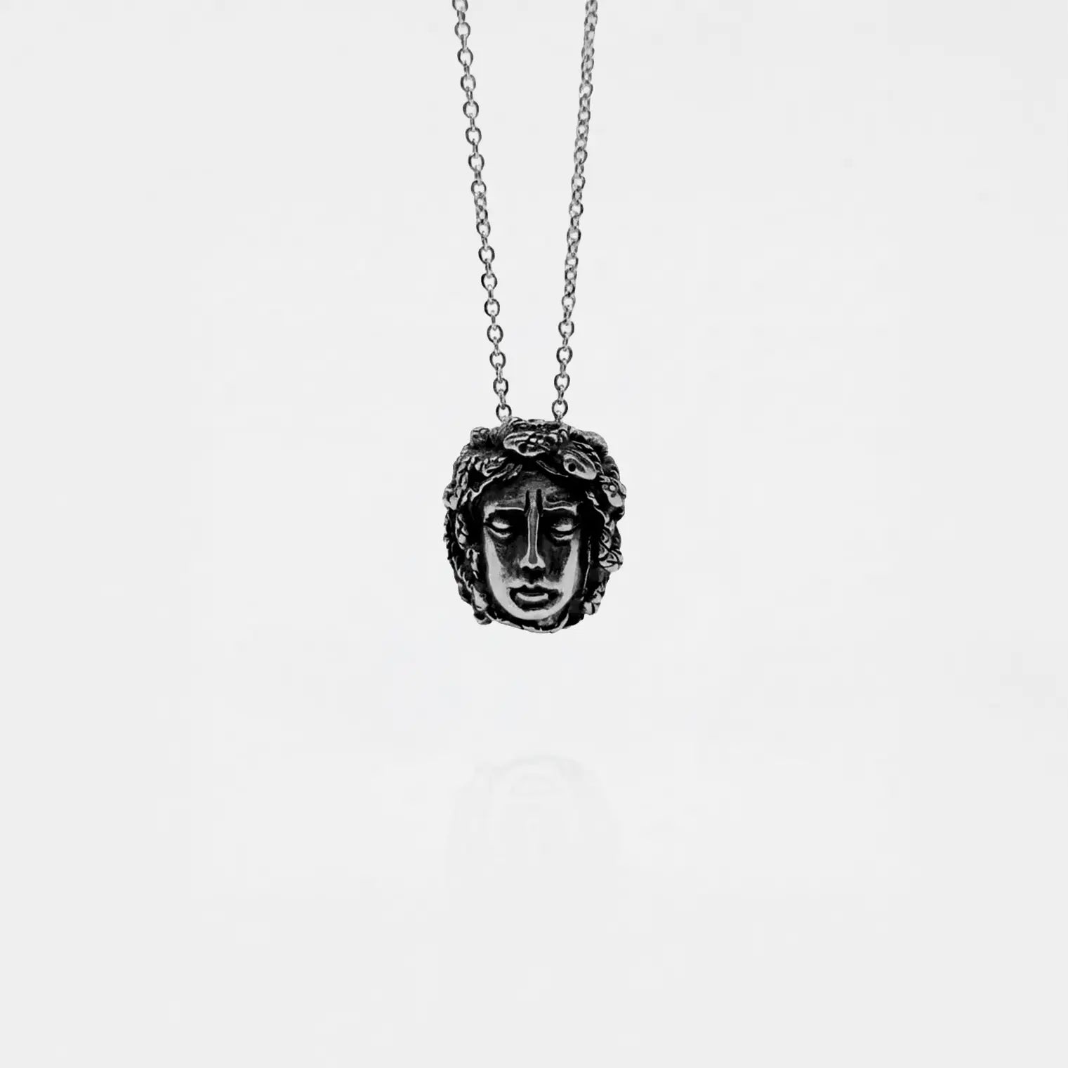 Necklace with a pendant featuring a medusa face design on a white background
