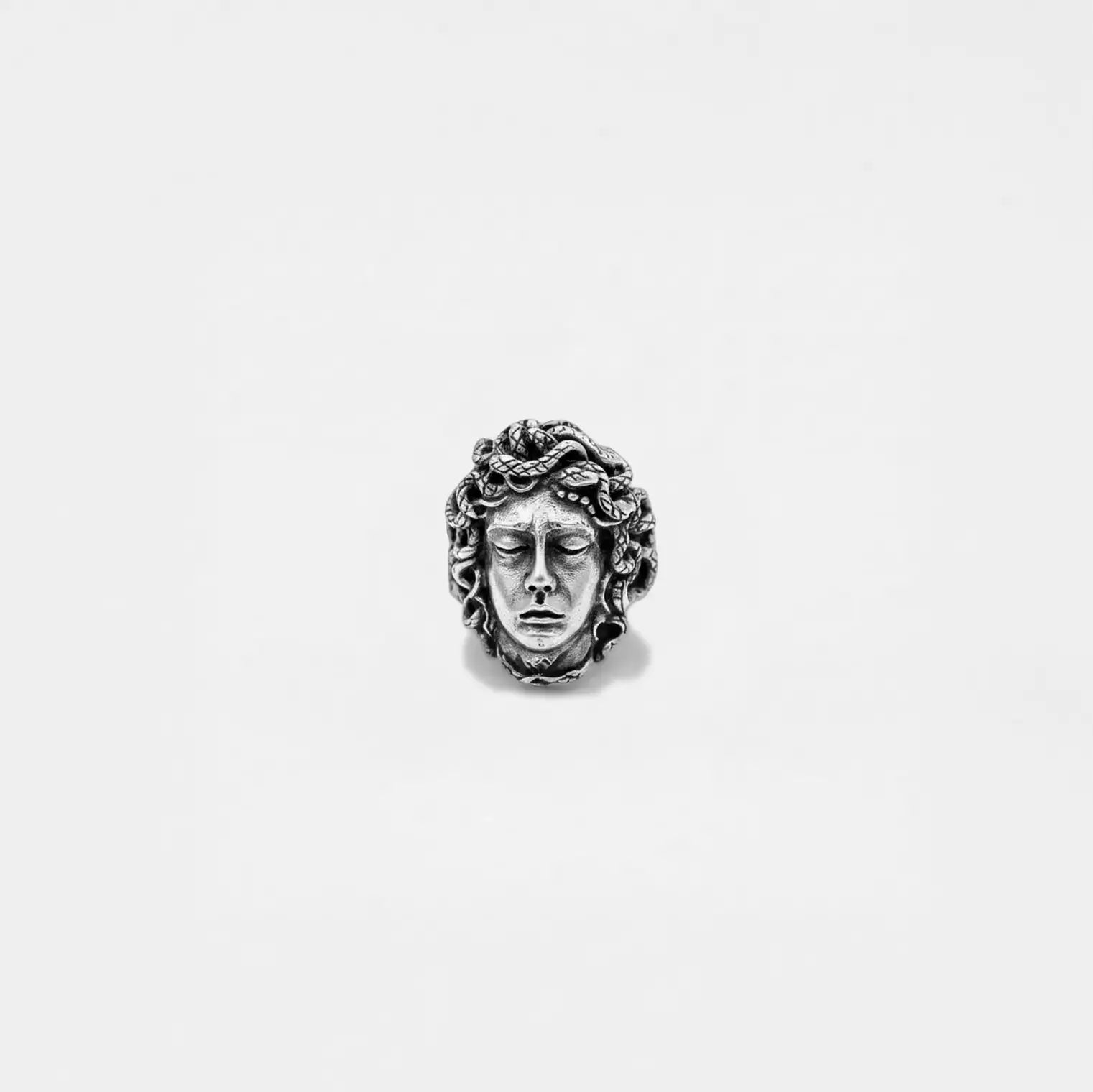 Silver pendant with a medusa face design on a white background