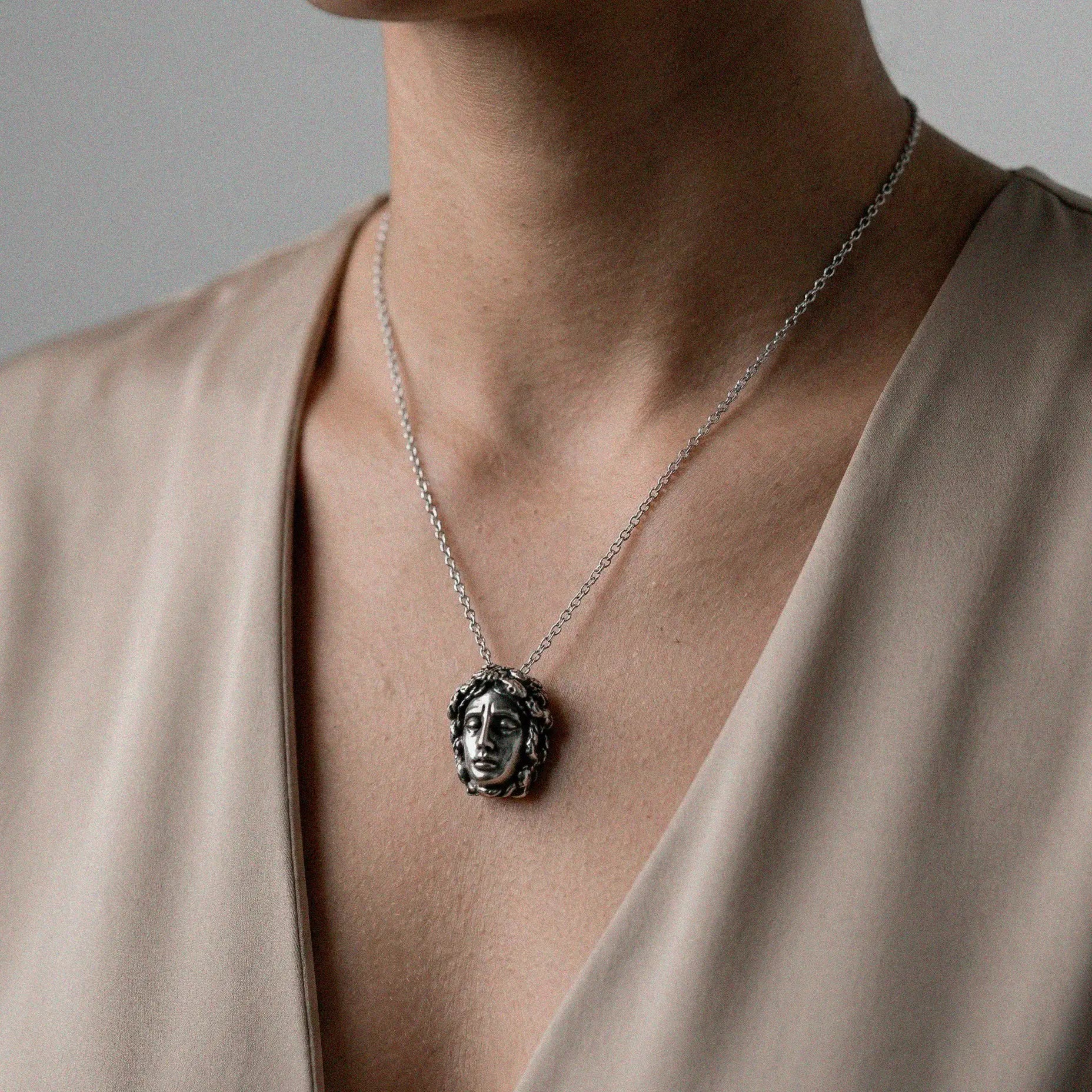 Necklace with a MEDUSA pendant worn by a person in a beige top against a neutral background