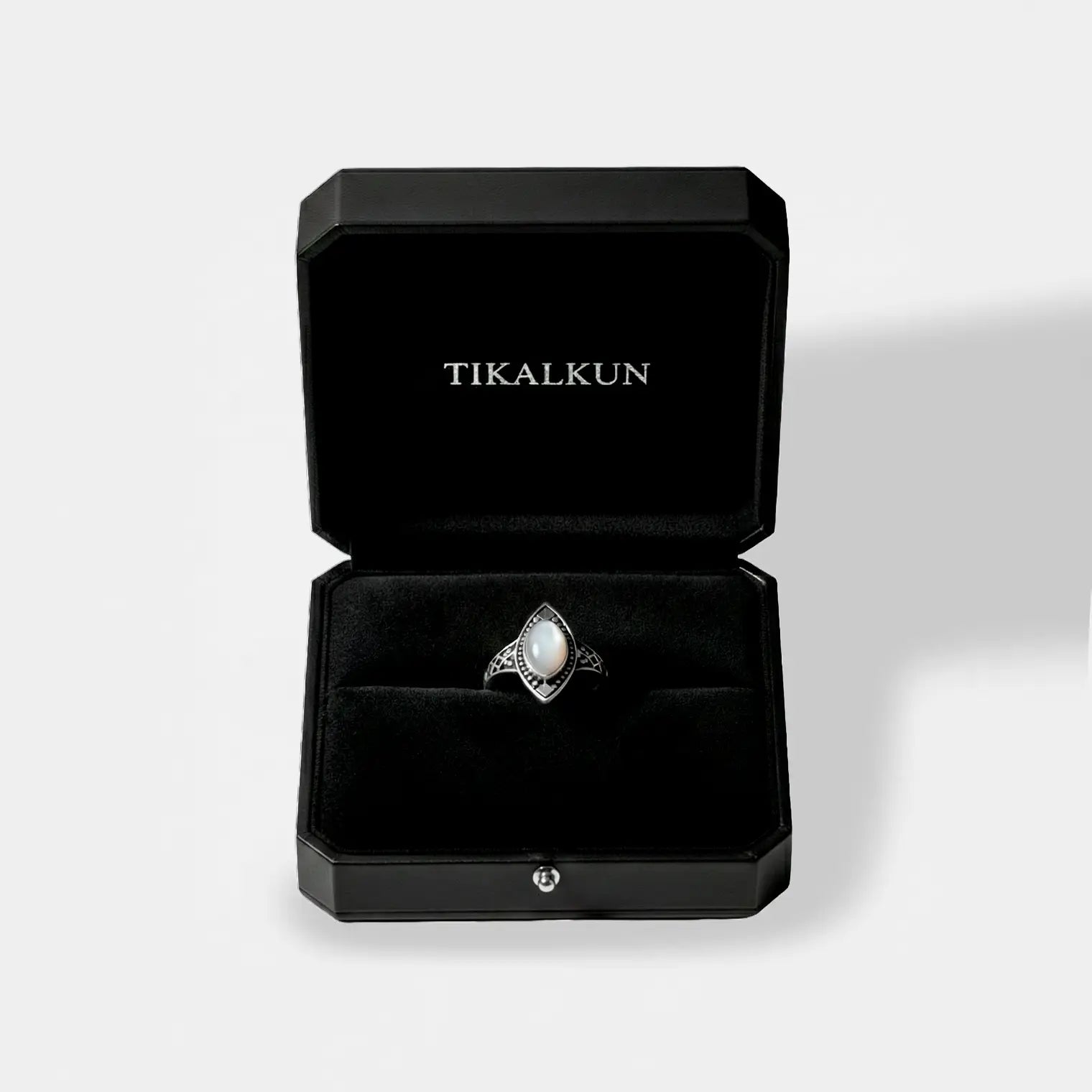 Jewelry box with a ring featuring a mother peal stone and silver accents, branded 'TIKALKUN'.