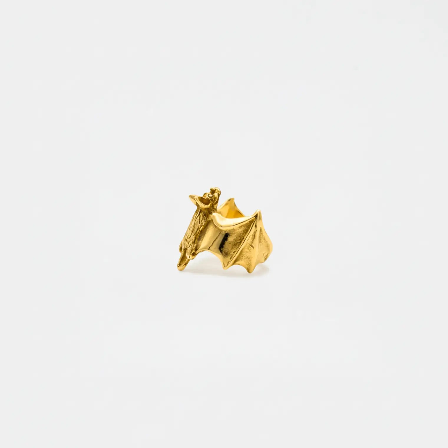 Gold bat-shaped earring on a white background