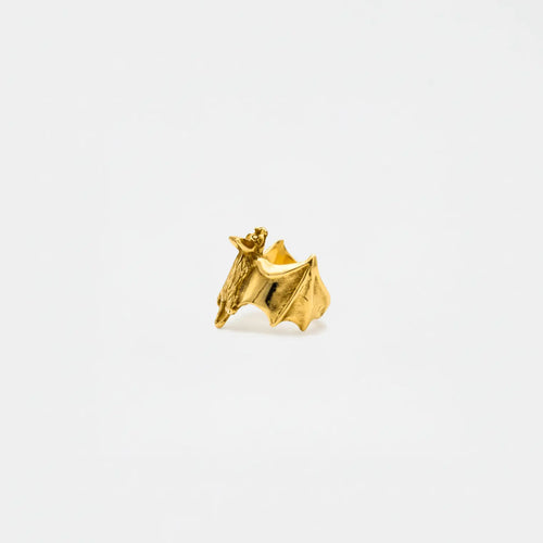 Gold bat-shaped earring on a white background