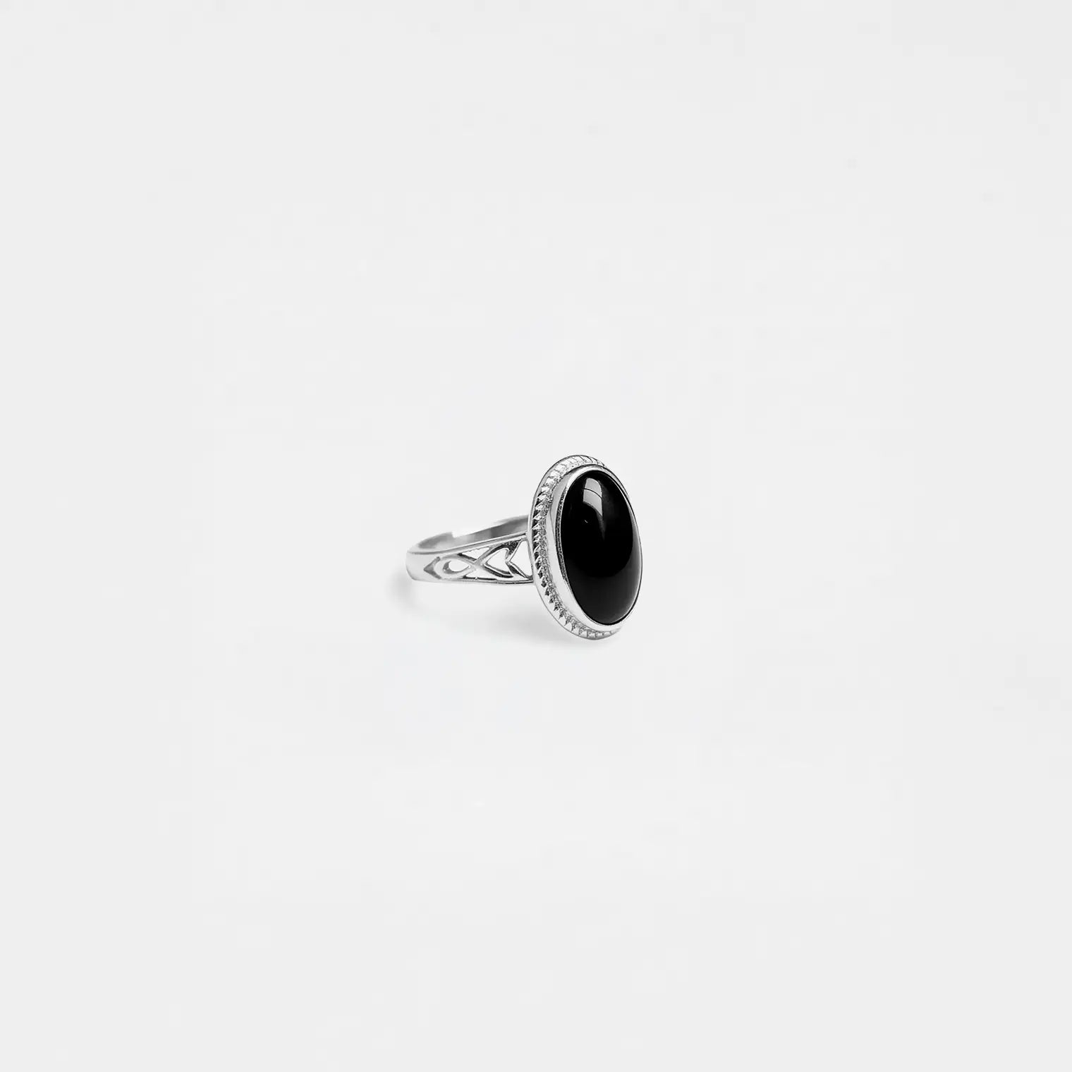 Silver ring with a black gemstone on a light gray background