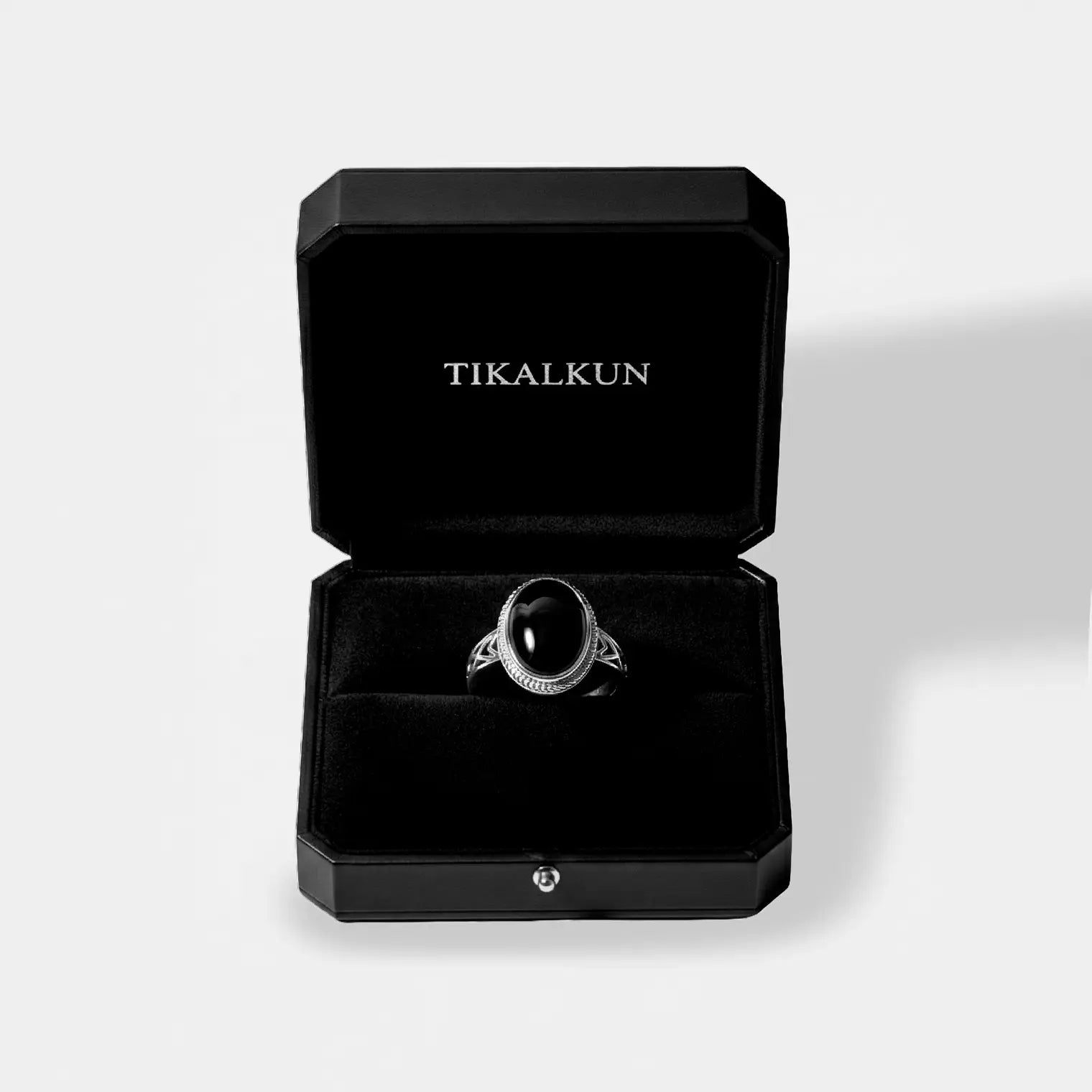 Silver ring with a black gemstone in a black Tikalkun box on a light gray background