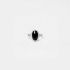 Silver ring with an obsidian gemstone on a light gray background