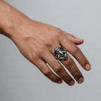 Hand wearing a silver ring with ganesha design on a gray background