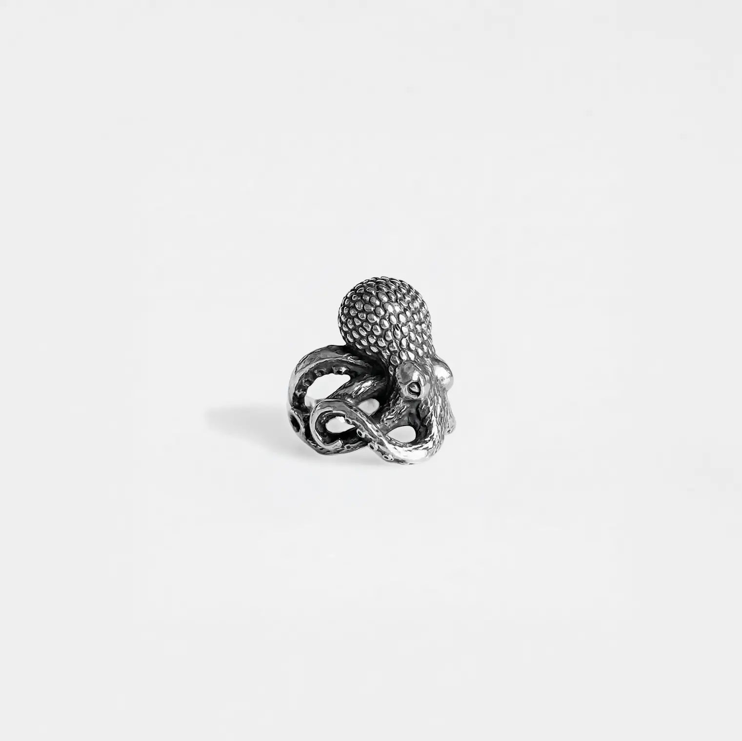 Silver ring with a octopus design on a light gray background