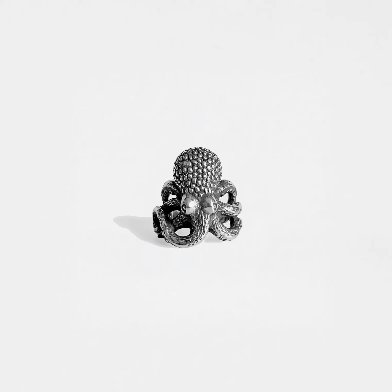 Silver octopus-shaped ring on a light gray background