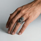 Hand wearing a silver ring with an octopus design on a light gray background