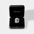 Black jewelry box with 'TIKALKUN' branding containing a silver olmec head ring