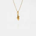 Gold orca pendant necklace on a thin chain against a light gray background