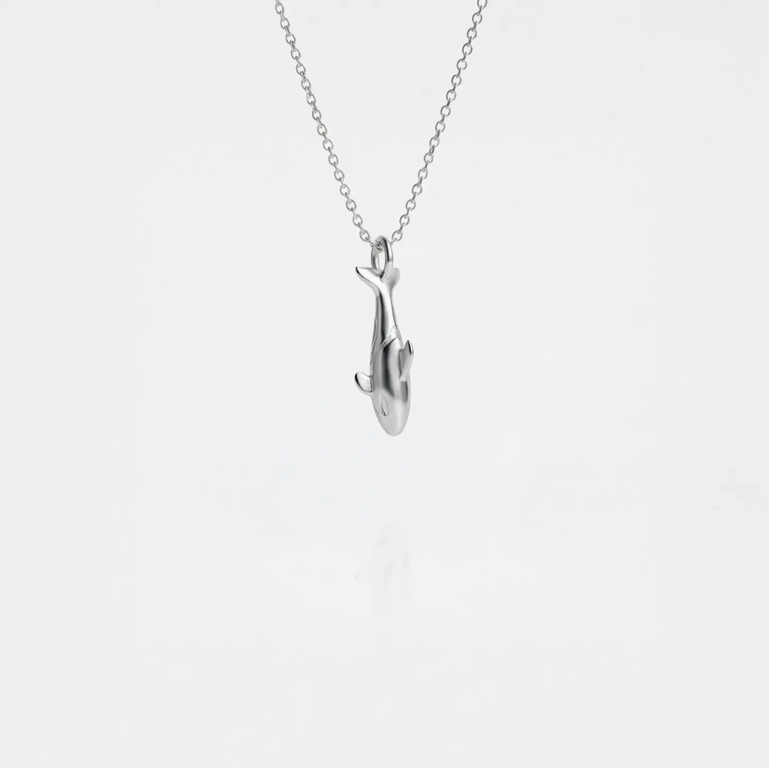 Silver orca pendant on a chain against a white background
